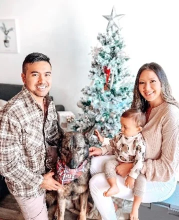 man and women with a dog near the christmas tree